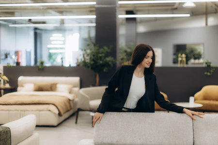 A woman in a furniture store examines a sofa surrounded by a contemporary interior design.の写真素材
