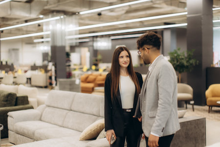 Two individuals engaging in a professional exchange in a contemporary space, emphasizing interactions within workplaces, collaboration, and modern office environments, surrounded by stylish furniture and practical decor.の写真素材