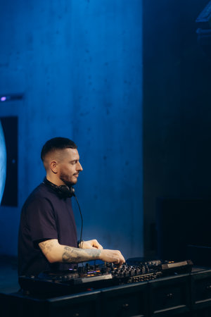 Skilled DJ performing music at an urban venue, surrounded by a captivating blue ambiance.の写真素材