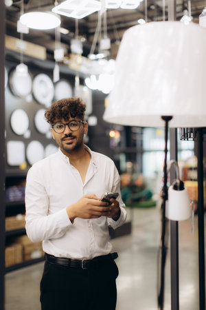 A well-dressed individual stands in a showroom surrounded by stylish modern lighting, suggesting confidence, professionalism, and contemporary lifestyle. The scene captures a blend of commercial and practical elegance.の写真素材