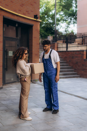 Courier delivering a package to a customer at a building entrance, showcasing the convenience of home delivery and efficient serviceの写真素材
