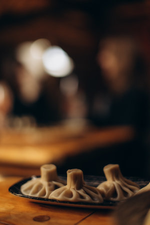 Steamed dumplings served on a plate, placed on a wooden table, with warm ambient lighting in the background creating a cozy dining atmosphere.の写真素材