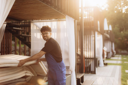 Young handyman arranging beach mattresses at a luxury resort, ensuring guest comfort and relaxationの写真素材