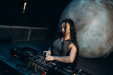 A female DJ skillfully mixes music on a professional DJ setup in a unique environment that features...