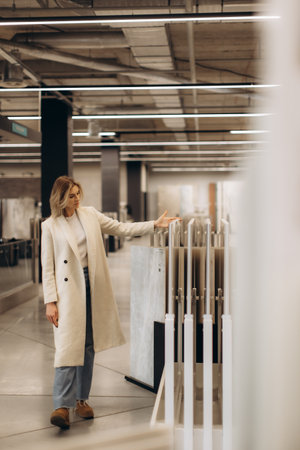 A stylish woman in a showroom evaluates tile samples, reflecting careful interior design choices. Modern lighting and industrial decor enhance the atmosphere, emphasizing a contemporary lifestyle and personal decision-making.の写真素材
