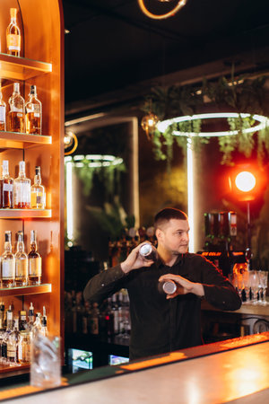 A professional bartender shakes two mixers to prepare a drink at a stylish bar, surrounded by a warm...
