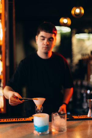 A bartender prepares a custom cocktail in a stylish bar with ambient lighting and drinks. The...