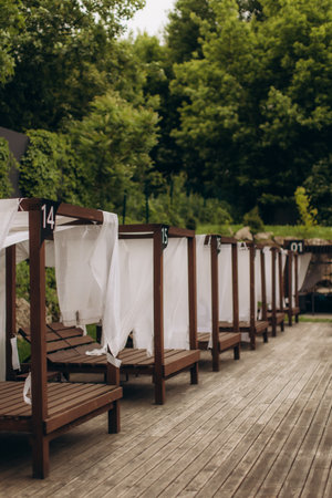 Luxurious wooden gazebos with white curtains offer a private and relaxing experience by the pool, creating a tranquil oasis for guests to unwindの写真素材