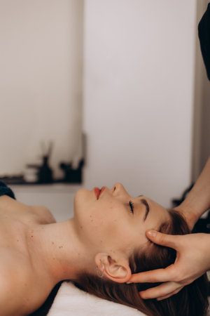 A serene spa setting featuring a relaxation head massage performed on a peaceful individual. Promotes wellness, tension relief, and soothing spa therapies.の写真素材