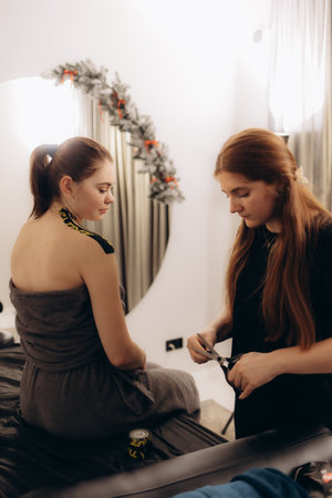 A professional beauty treatment session with two women in a serene spa environment. The atmosphere is relaxing with festive decorations in the background, highlighting a focus on wellness and tranquility.の写真素材