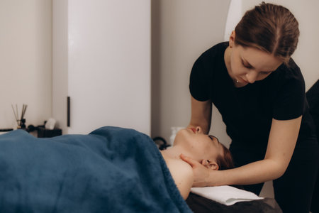 A masseuse expertly performs a neck massage on a relaxed client in a tranquil spa environment, promoting wellness and relaxation.の写真素材