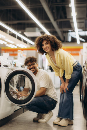 A cheerful couple explores washer options in a modern electronics store, enthusiastically discussing their purchase.の写真素材