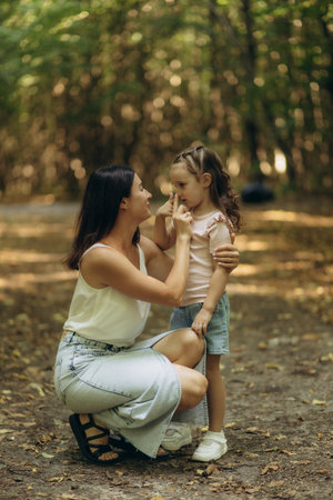 A tender moment between a mother and her child in a serene forest setting, expressing care and connection. Perfect depiction of motherhood, outdoors, and family bonding in a natural environment.の写真素材