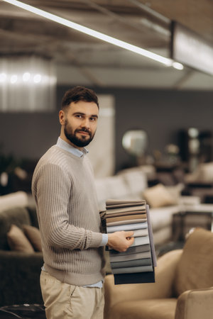A stylish individual showcasing a selection of fabric samples in an elegant furniture store. Sophisticated design and attention to detail highlight contemporary interior fashion trends.の写真素材