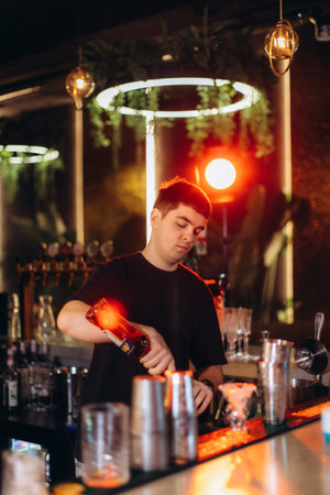 Bartender mixes a drink in a stylish bar setting, artfully lit with warm ambiance.