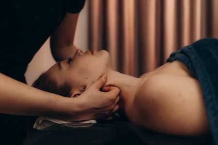 A serene spa environment featuring a therapist performing a neck massage, promoting relaxation and wellness. Perfect for concepts of self-care, health, and stress relief.の写真素材