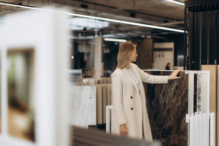 Elegant woman browsing various material options in a stylish showroom, focusing on marble textures. Perfect setting for home improvement concepts and modern interior designs.の写真素材