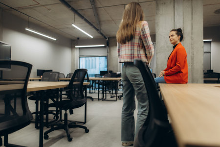 Two colleagues engage in a friendly discussion in a contemporary and open workspace, highlighting...
