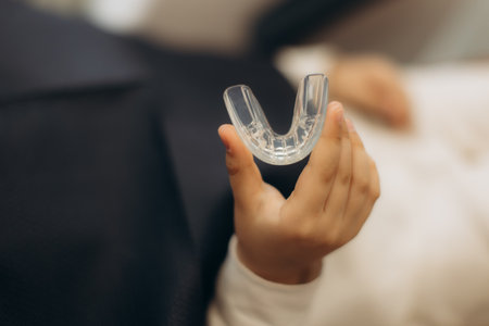 Hand holding a transparent dental guard, emphasizing the importance of dental care and protection for oral health and wellnessの写真素材