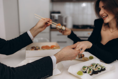 A couple shares a romantic meal of sushi, enjoying a relaxed and intimate moment together at home, showcasing love and connection.の写真素材