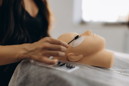 Beautician applying individual led eyelash extensions to a mannequin head, practicing beauty salon...