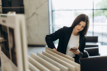 Professional woman in a contemporary setting exploring choice samples. Stylish, confident, multitasker, professional business environment.の写真素材