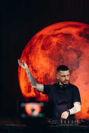 A vibrant image of a DJ engrossed in his performance, accompanied by a dramatic red planet-themed backdrop, creating an electrifying atmosphere.の写真素材