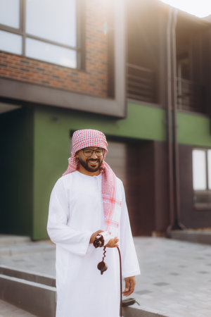 Arab man wearing traditional clothing holding a charger, symbolizing sustainability and modern technologyの写真素材
