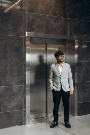 A well-dressed individual stands near an elevator, showcasing professionalism and modern...