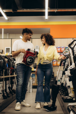 Two individuals explore a well-organized electronics store, discussing and selecting modern vacuum models together.の写真素材