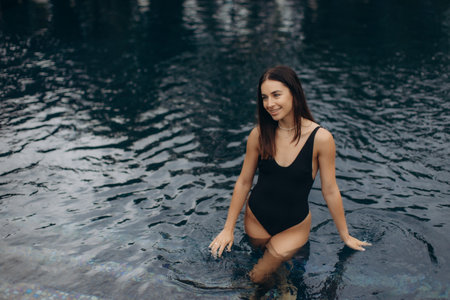Tourist enjoying a refreshing dip in a swimming pool, soaking up the sun during a blissful summer vacation at a luxurious resortの写真素材