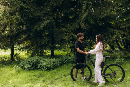 Man and woman enjoying an outdoor bike ride, stopping for a conversation, connecting and sharing a loving moment in natureの写真素材