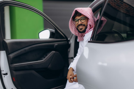 Arab man smiling, wearing traditional headscarf and thobe. Combining modern luxury with traditional lifestyleの写真素材