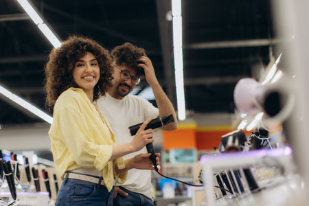 A happy couple explores and evaluates electronic devices in a bright, modern store environment. They enjoy selecting the perfect product while surrounded by various technology options.の写真素材