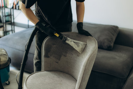 Professional worker performing dry cleaning on a dirty upholstered chair, restoring its clean appearance in a home settingの写真素材