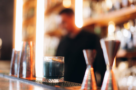 A stylish bar setting with a focus on a beautifully crafted cocktail placed on the counter,...