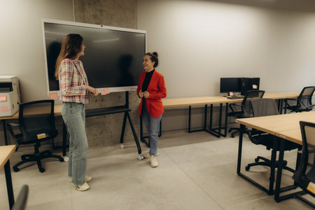 Colleagues interact in a contemporary office equipped with desks and a large screen, fostering a professional atmosphere. Enhanced by their collaboration, the image reflects workplace engagement and technological productivity.の写真素材
