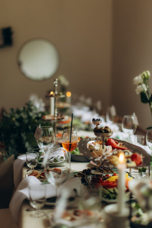 Well-arranged dinner table with various appetizers and drinks for a celebration or catered event, featuring a vibrant aperol spritzの写真素材