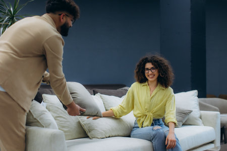 Happy young couple choosing new furniture, focusing on comfort and style while shopping for a sofa in a modern storeの写真素材