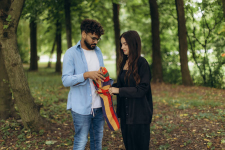 Young couple preparing a vibrant hammock in a green park, anticipating a peaceful moment of shared leisure and outdoor comfortの写真素材
