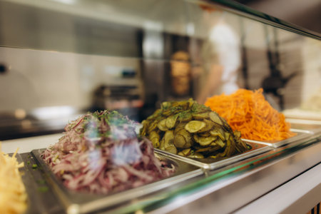 Pickled cucumbers, red onion, and shredded carrots displaying inside a restaurant countertop, ready for preparing street foodの写真素材