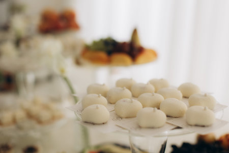 Elegant dessert table centerpiece with individual white mousse pastries serving guests at a special celebration or party cateringの写真素材