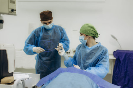 Medical team performing an operation, handling instruments during a surgical intervention in a hospital operating roomの写真素材