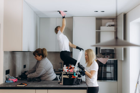 Cleaning team providing professional service, meticulously cleaning appliances and fixtures in a bright, modern kitchenの写真素材