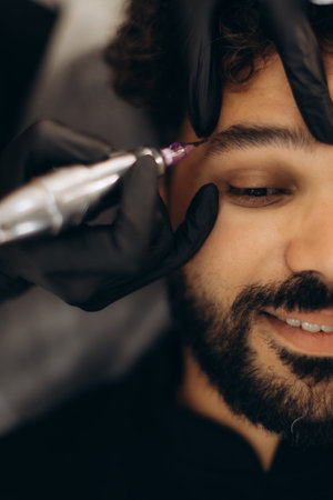 Male client undergoing eyebrow microblading, adding definition and density to his facial hair....