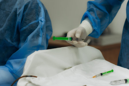 Healthcare worker in gown and gloves holding a syringe, preparing medication for patient treatment