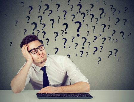 Young procrastinating office employee sitting in laziness at desk and looking away in ignorance.