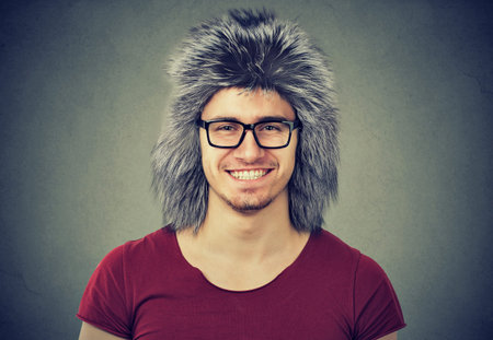 Handsome smiling man in casual t-shirt and eyeglasses wearing warm winter hat smiling at camera. 