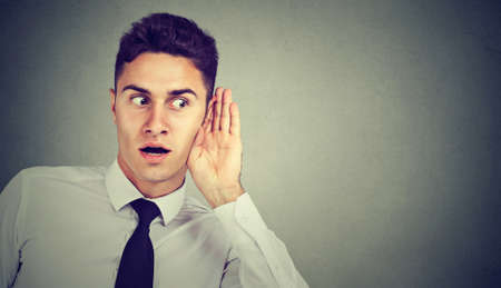 Portrait of handsome business man secretly listening on private conversation. Human face, expression, emotion, body language.の写真素材