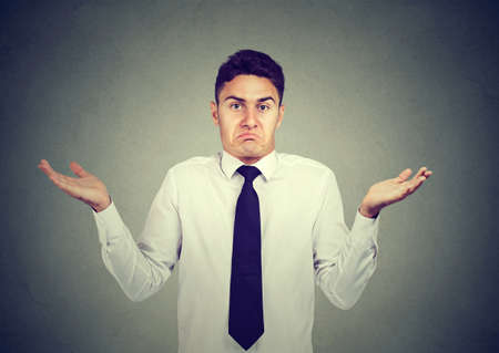 Closeup portrait young business man shrugging shoulders isolated on gray wall background. Body languageの写真素材